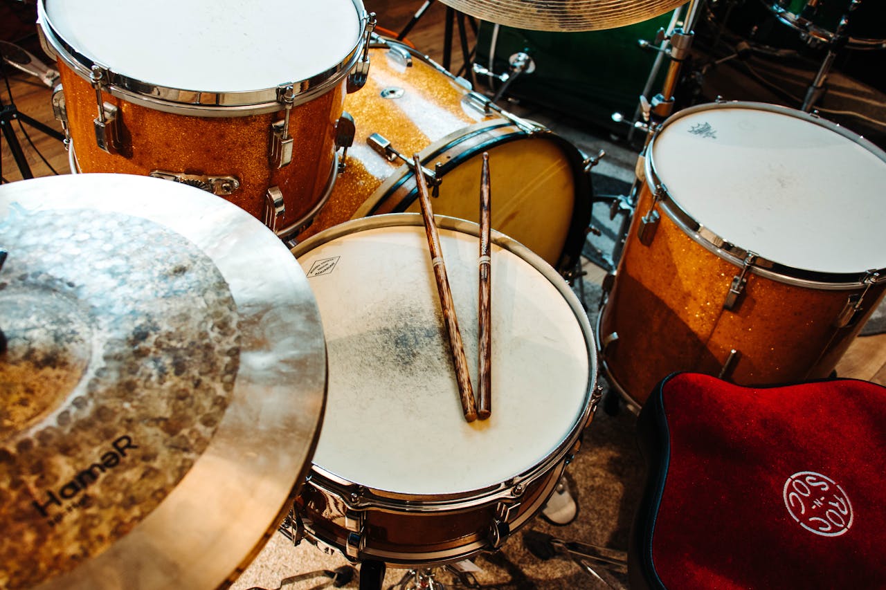 Close-up of a drum set with drumsticks in a music studio, showcasing percussion instruments.