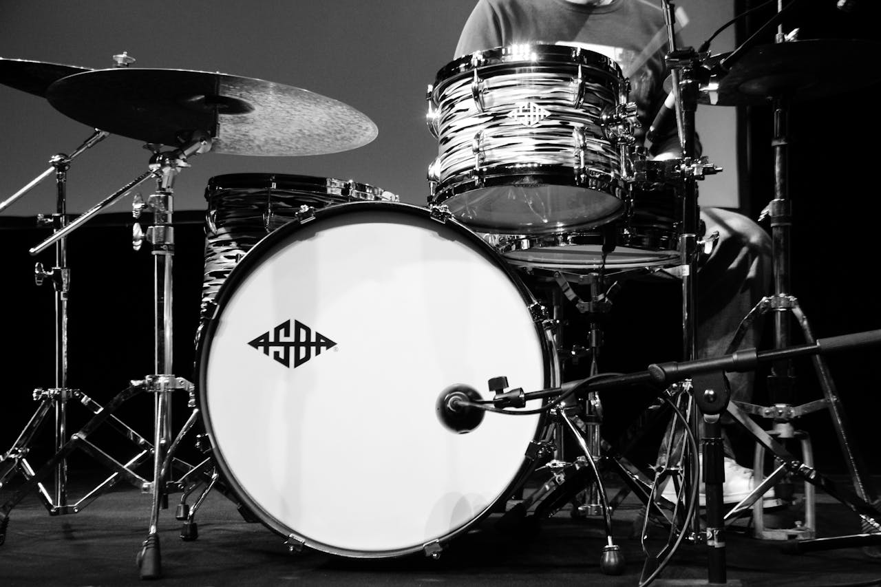 Black and white close-up of a drum set with a logo, captured in a studio setting.