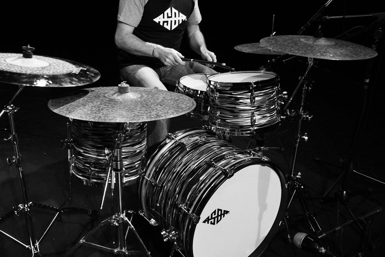 A drummer performing on a vintage drum set in a studio setting.