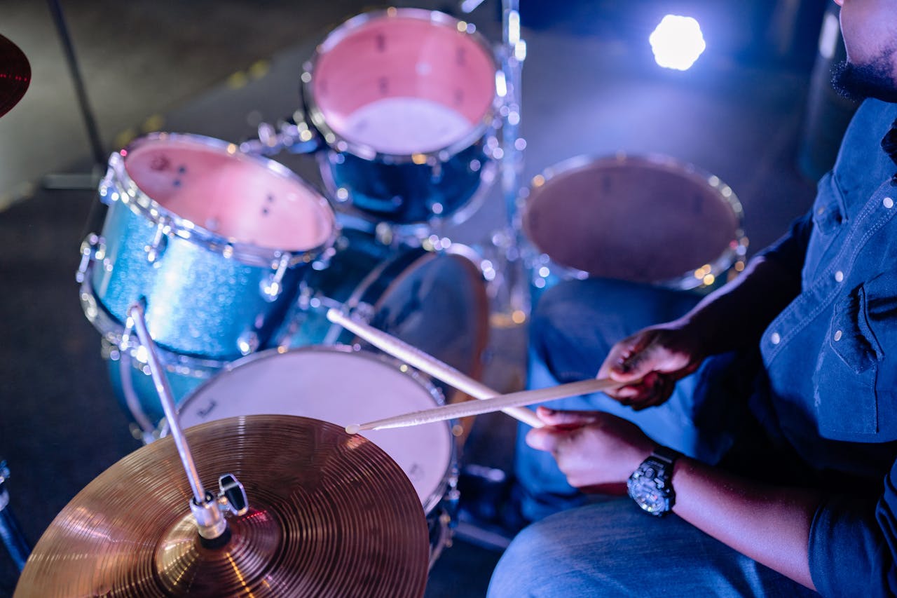 Musician performing on drum set with focus on hands and drum sticks.